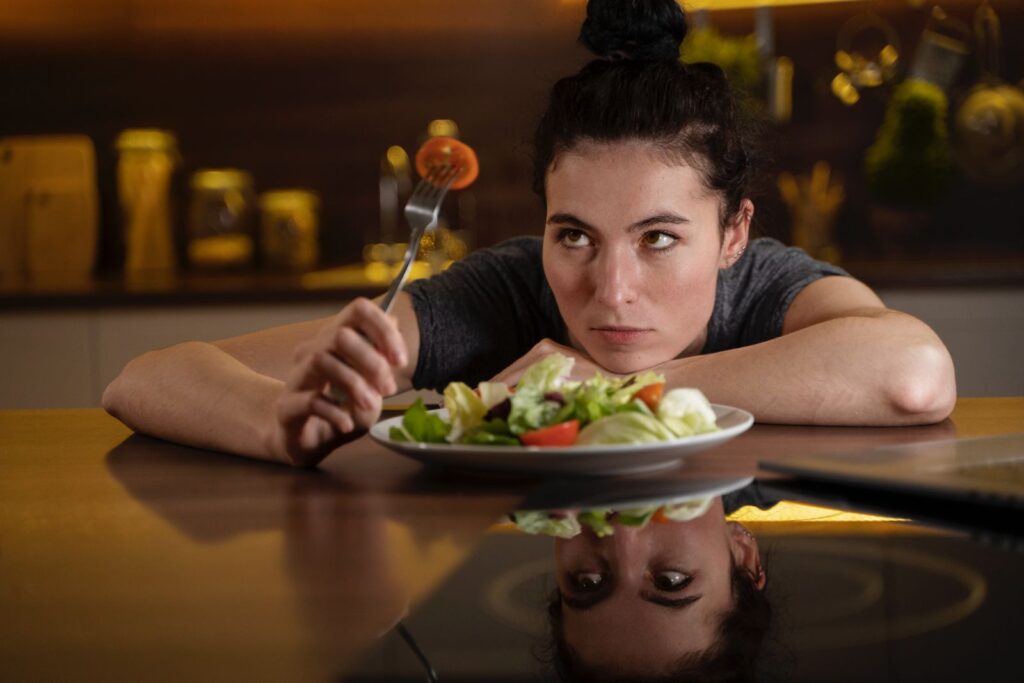 Nő ül egy asztalnál egy tányér salátával teli tányér előtt